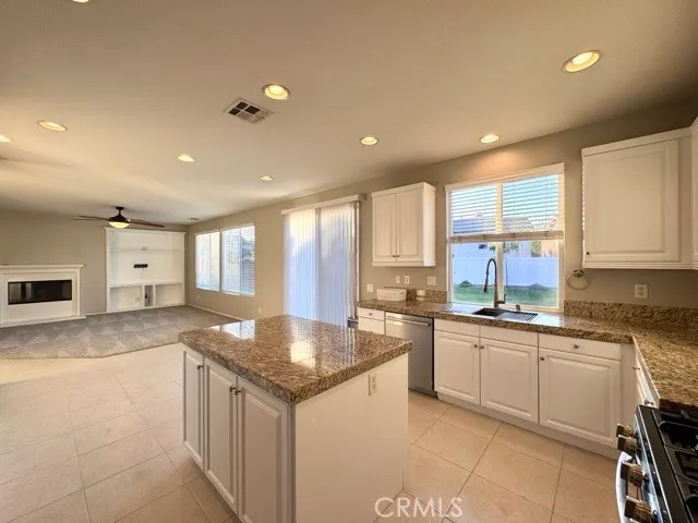 a large kitchen with kitchen island a stove a refrigerator a sink dishwasher and white cabinets with wooden floor