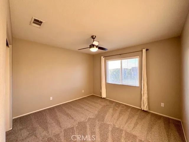 a view of a livingroom with a ceiling fan & windows