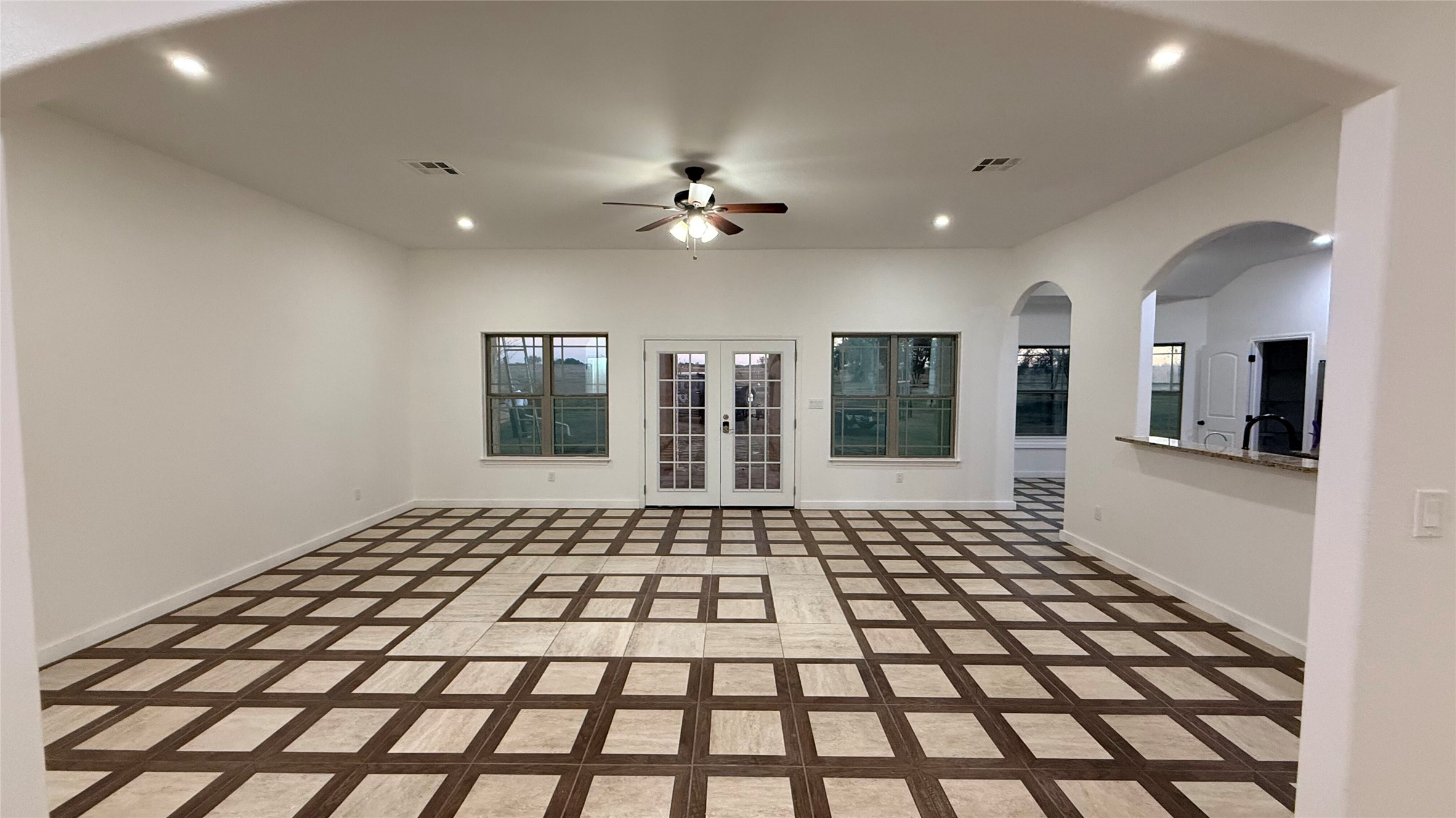 5673 Solana Ranch Road Salado, TX 76571 - Photo 1 of 1 Empty room with arched walkways, inlaid floor details, recessed lighting, ceiling fan, and french doors