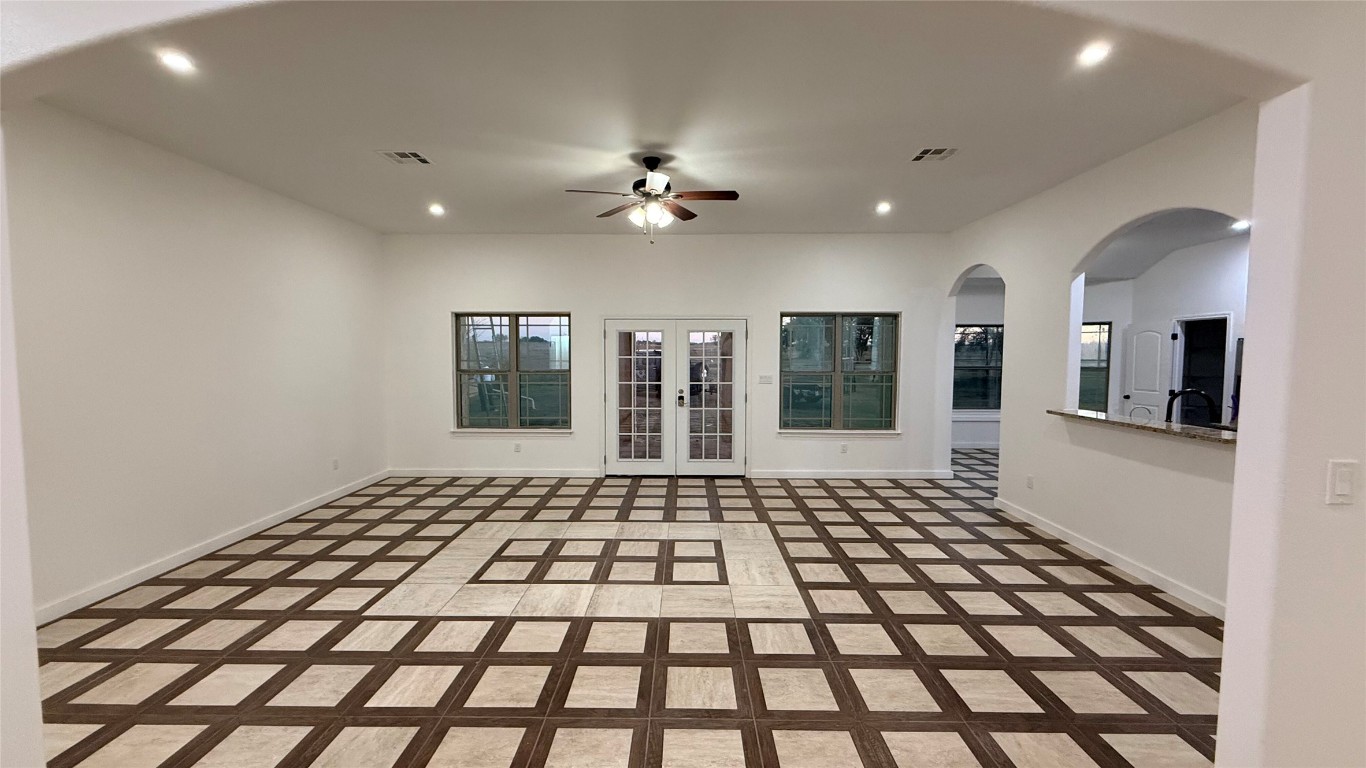 a view of a big room with windows and chandelier fan