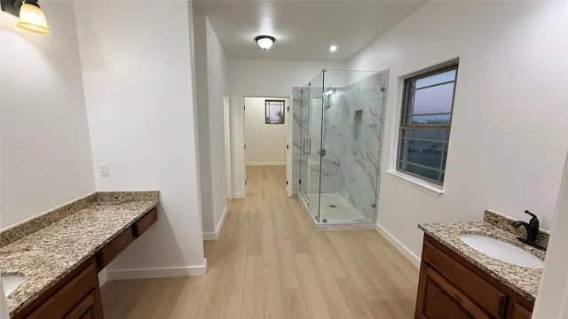 a bathroom with a granite countertop sink a mirror and shower