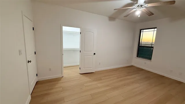 an empty room with a ceiling fan and wooden floor