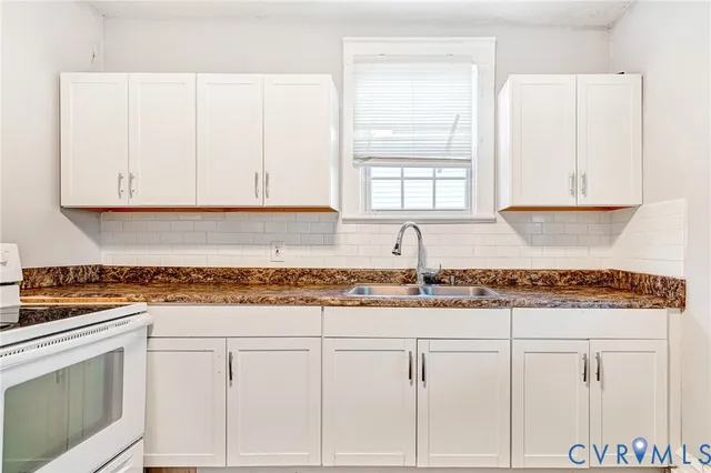 a kitchen with granite countertop white cabinets and a stove