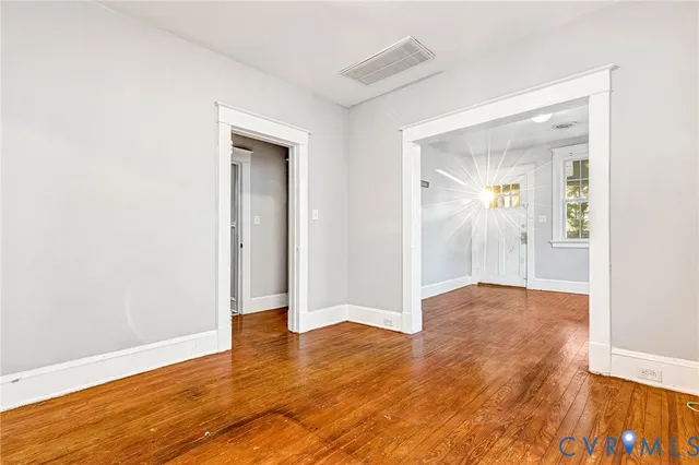 an empty room with wooden floor and mirror