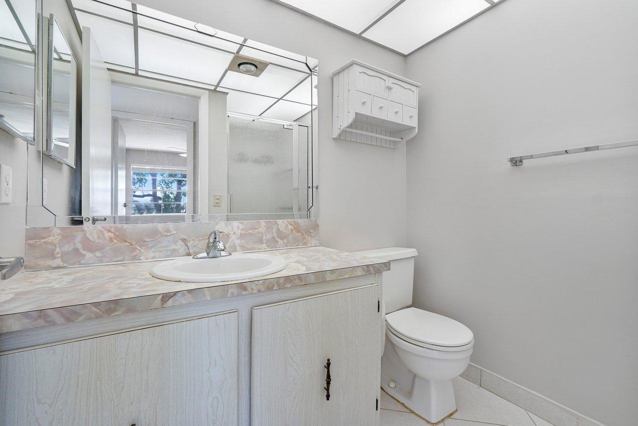 77 Normandy B Delray Beach, FL 33484 - Photo 12 of 34 a bathroom with a granite countertop sink a toilet and a mirror