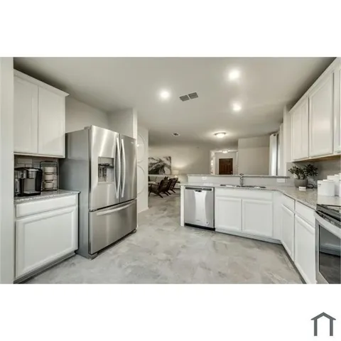 a kitchen with a refrigerator and white cabinets