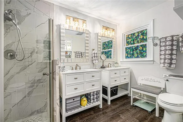 a bathroom with a double vanity sink toilet and next to a window