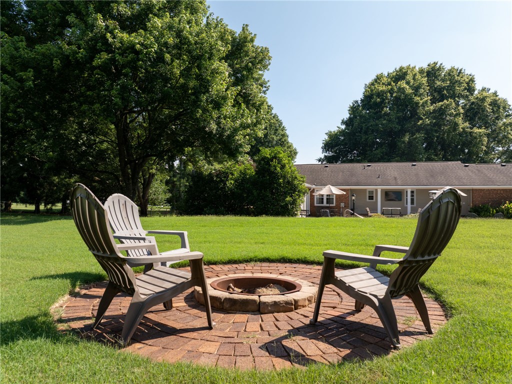 3513 Hopewell Road Anderson, SC 29621 - Photo 42 of 50 A verdant lawn creates a peaceful outdoor setting, featuring a brick-surrounded fire pit.