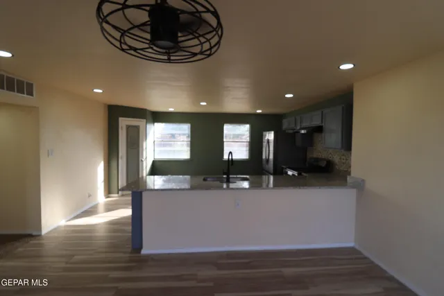 an empty room with wooden floor cabinet and windows