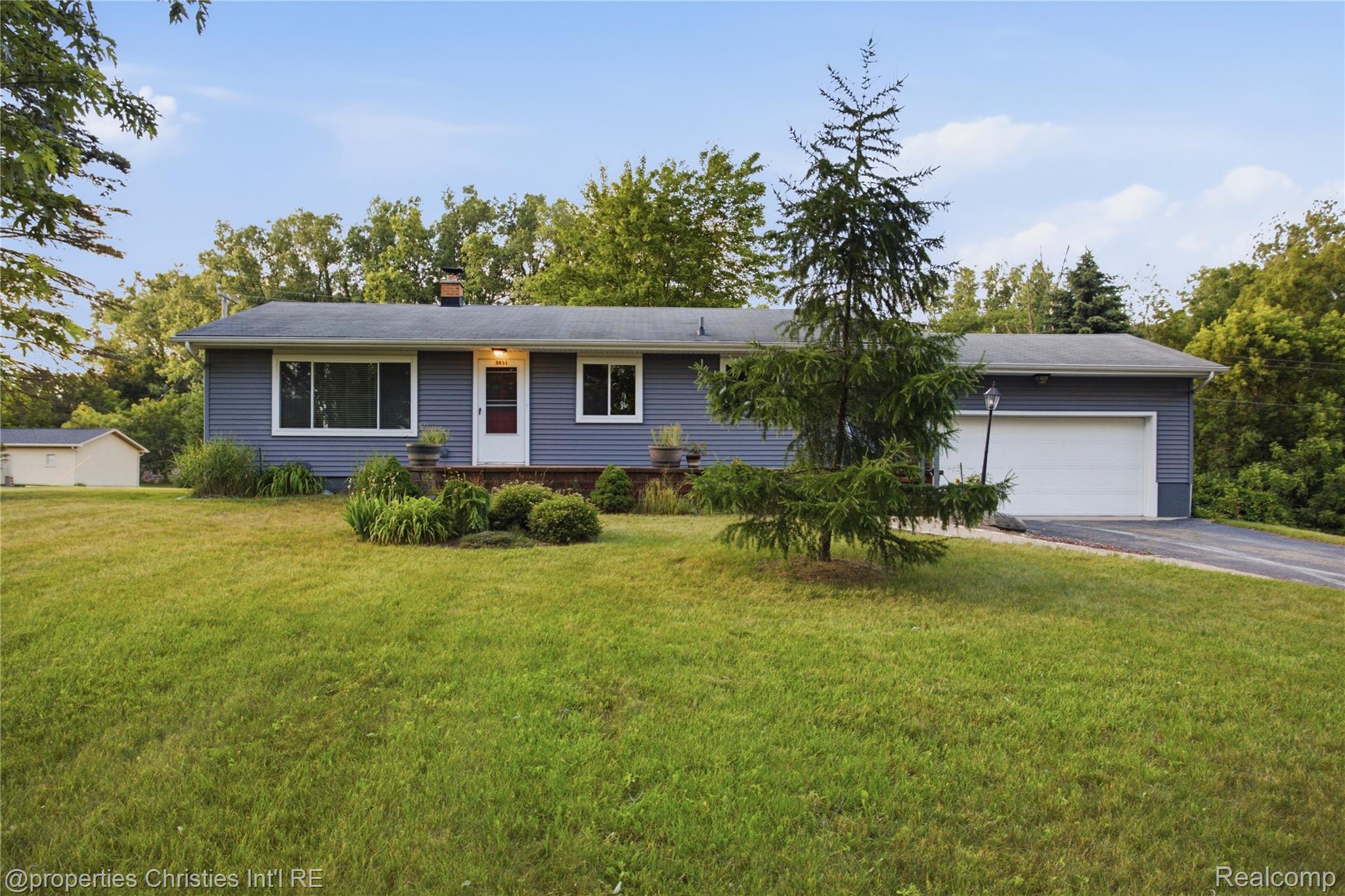 3851 Judd Road Milan, MI 48160 - Photo 1 of 41 Ranch-style residence featuring blue horizontal siding, white trim, and a prominent front door with storm door