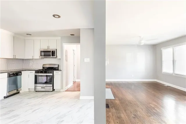 a view of a kitchen with a sink stove cabinets and empty room