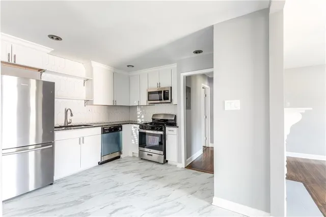 a kitchen with stainless steel appliances granite countertop a refrigerator stove and sink