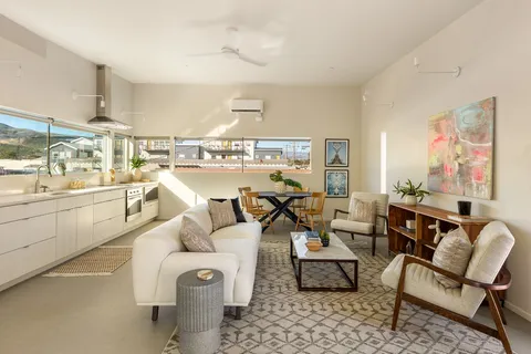 a living room with furniture and a large window with kitchen view