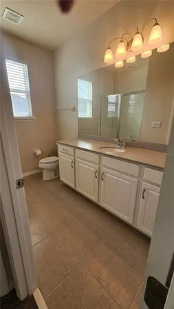 a bathroom with a double vanity sink a toilet and a mirror