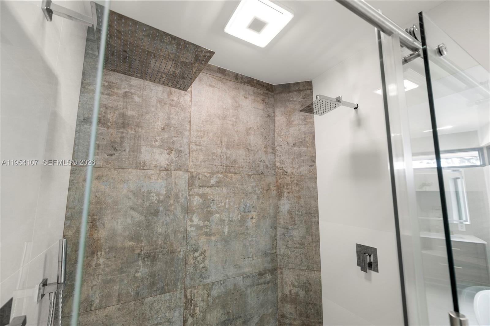 3910 Northeast 27th Terrace Lighthouse Point, FL 33064 - Photo 33 of 55 a bathroom with a glass shower door and mirror