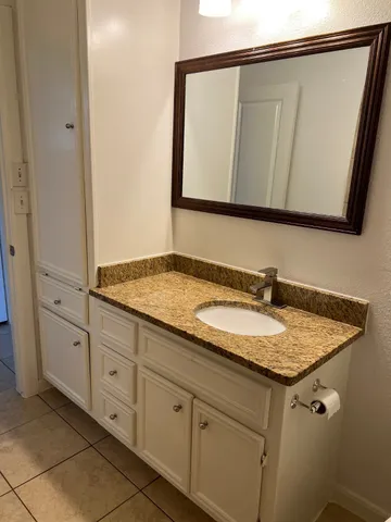 a bathroom with a granite countertop sink and a mirror