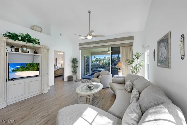 a living room with furniture a flat screen tv and a floor to ceiling window