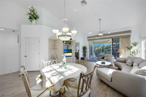 a view of a dining room with furniture a chandelier and large windows