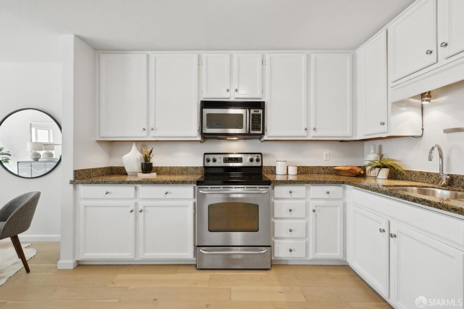 550 South Van Ness Avenue, Unit 207 San Francisco, CA 94110 - Photo 11 of 22 a kitchen with granite countertop white cabinets and stainless steel appliances