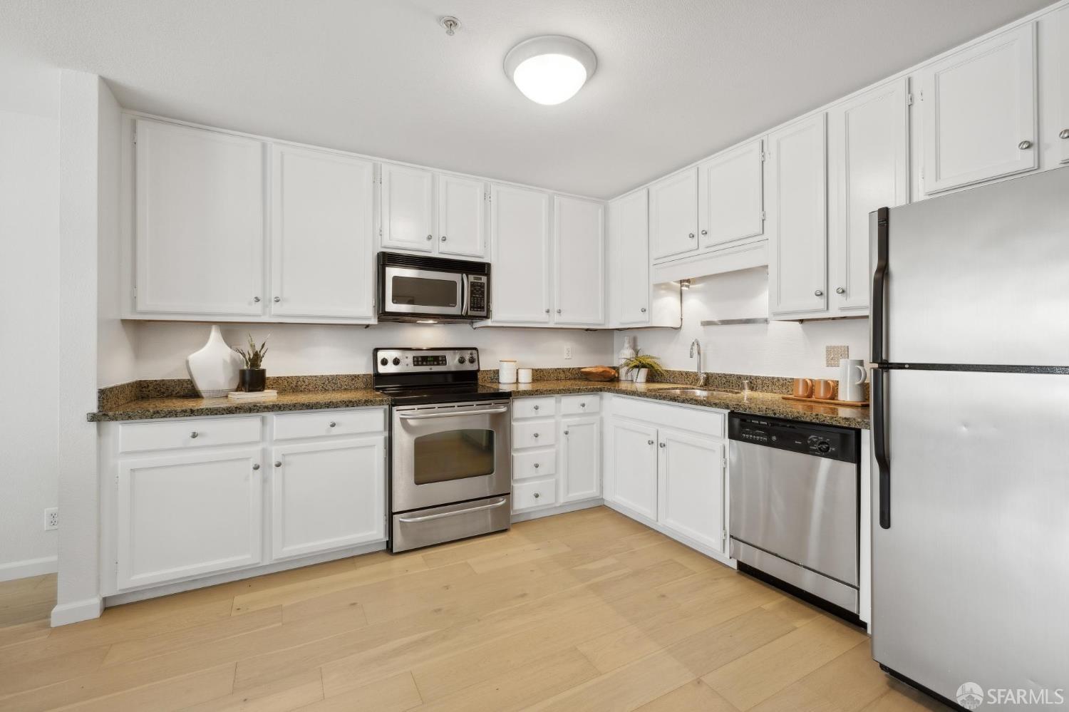 550 South Van Ness Avenue, Unit 207 San Francisco, CA 94110 - Photo 10 of 22 a kitchen with granite countertop white cabinets and stainless steel appliances