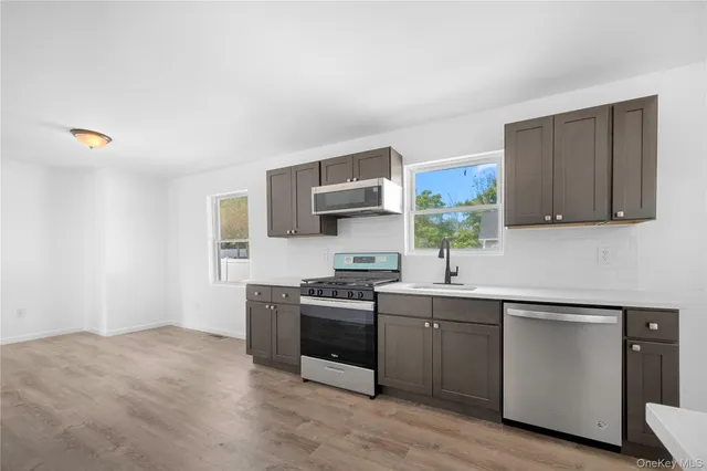 a kitchen with stainless steel appliances granite countertop a stove a sink and a microwave