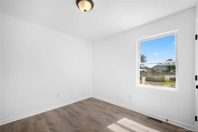 an empty room with wooden floor and window