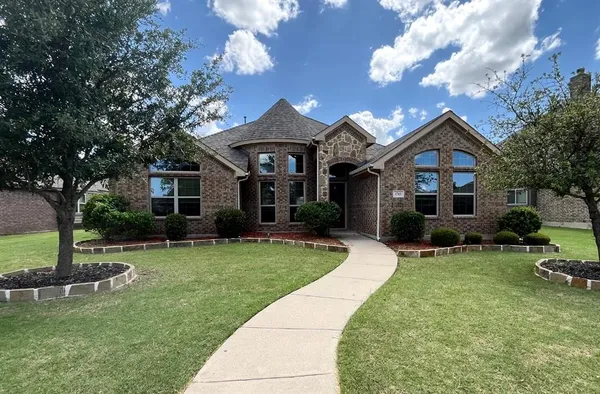 a front view of a house with a garden and trees