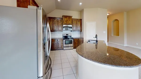 a kitchen with stainless steel appliances granite countertop a sink a stove and refrigerator