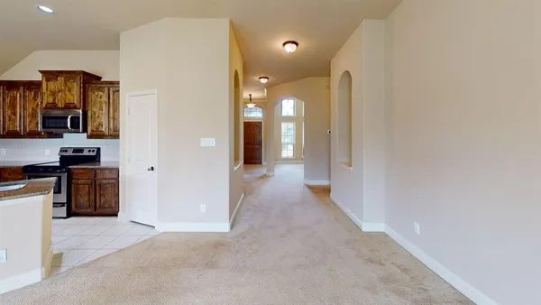 a view of a hallway with stainless steel appliances granite countertop cabinets and stove