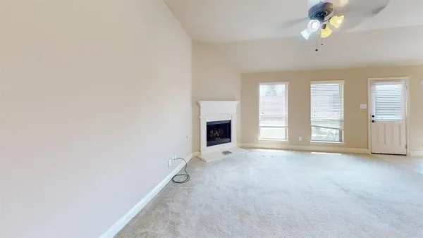 an empty room with chandelier fan and windows