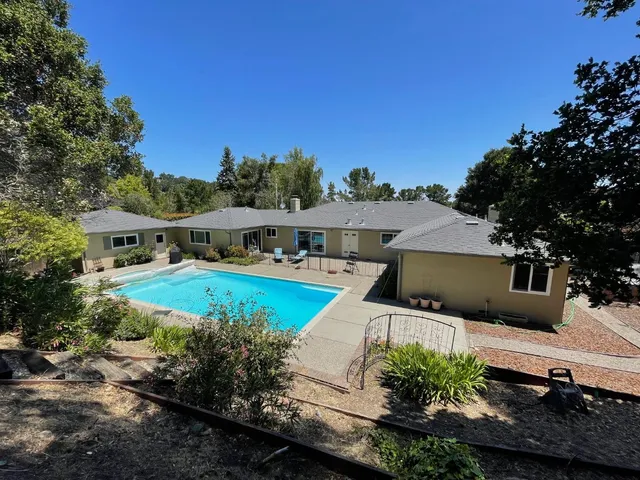 a view of a house with pool and a yard