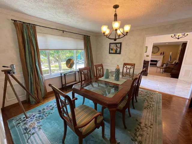 a dining room with wooden floor a chandelier a wooden table and chairs