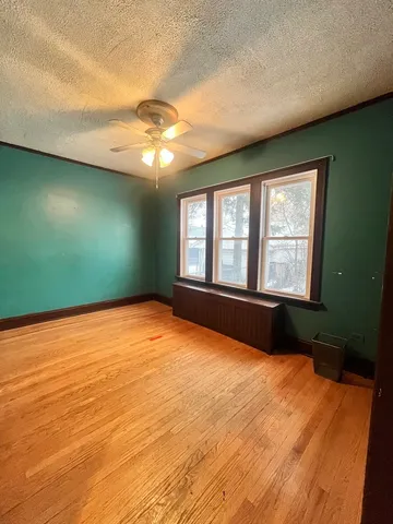 a view of an empty room with window and chandelier fan
