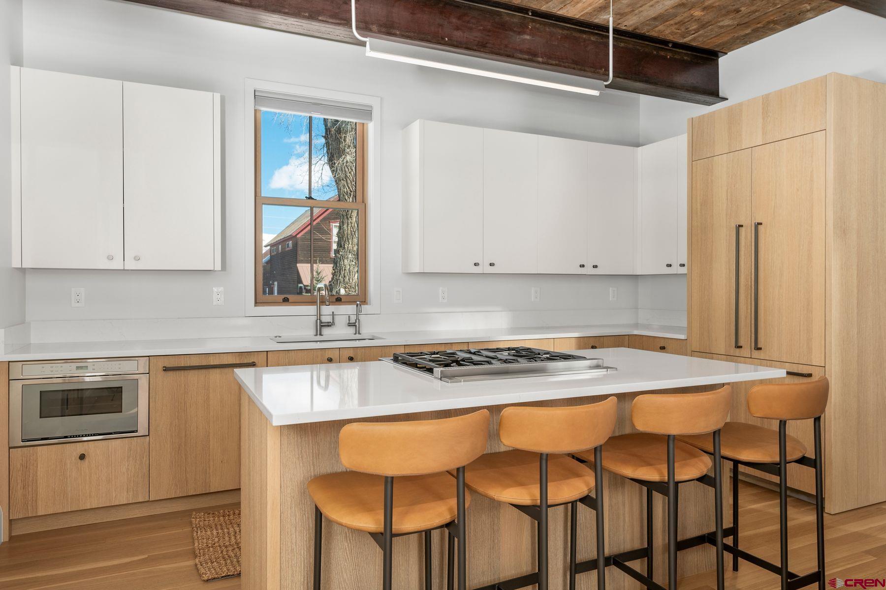 304 2nd Street Crested Butte, CO 81224 - Photo 7 of 37 a kitchen with stainless steel appliances granite countertop a table chairs sink and cabinets