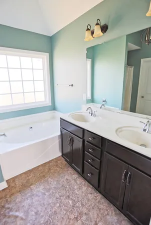 a spacious bathroom with a tub sink and mirror