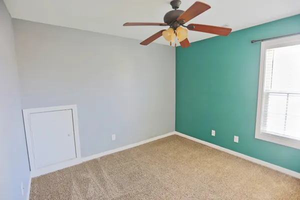 an empty room with a window and a fan