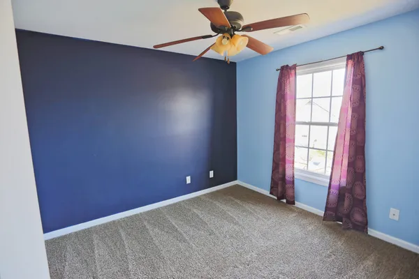 an empty room with windows and fan