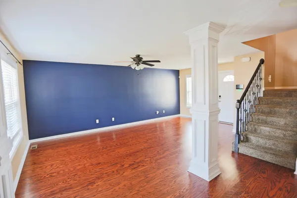 a view of an empty room with wooden floor and stairs