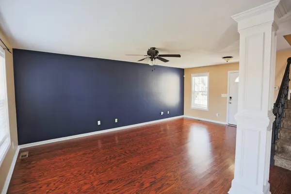 a view of an empty room with window and wooden floor