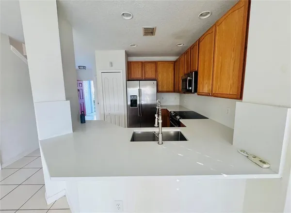 a kitchen with stainless steel appliances a sink a refrigerator a microwave a sink and cabinets