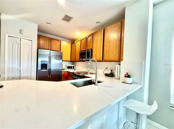 a kitchen with stainless steel appliances a sink a stove a refrigerator a center island and furniture