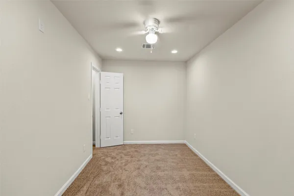 an empty room with a ceiling fan and carpet