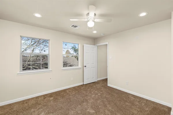 an empty room with windows and ceiling fan