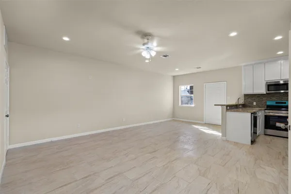 a view of a kitchen with a sink and dishwasher a stove top oven with white cabinets