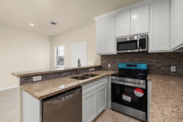 a kitchen with stainless steel appliances granite countertop a stove and a microwave