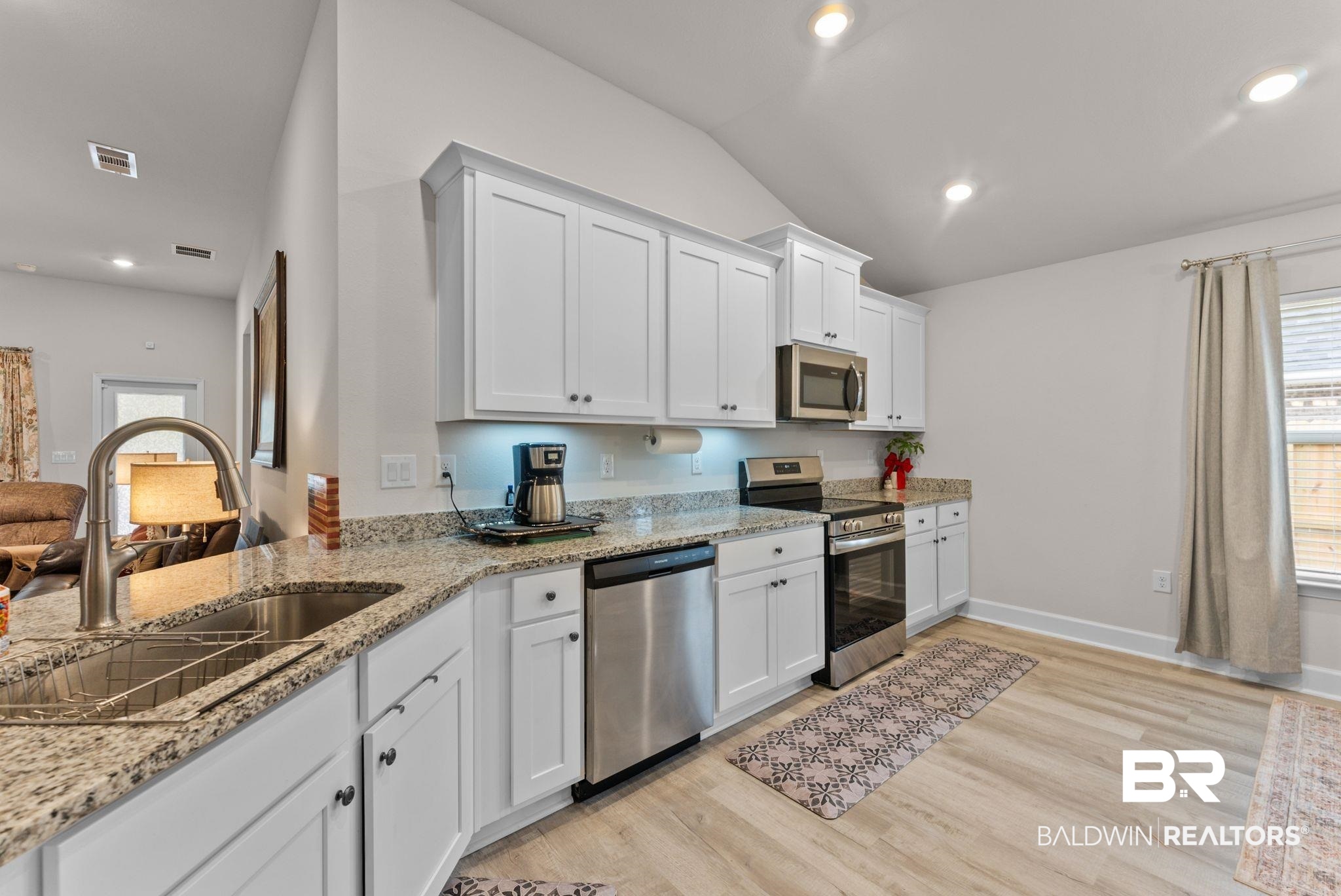 692 Mayflower Drive Foley, AL 36535 - Photo 16 of 40 Kitchen featuring healthy amount of natural light, stainless steel appliances, white cabinets, light stone countertops, and lofted ceiling