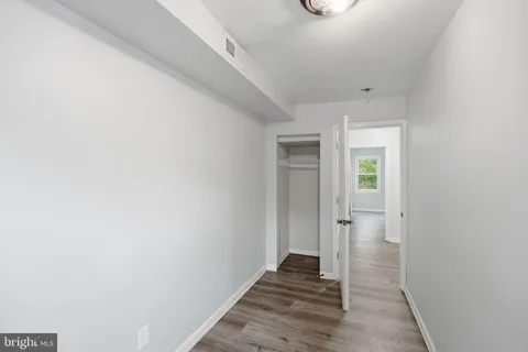 a view of a hallway with wooden floor and a bathroom