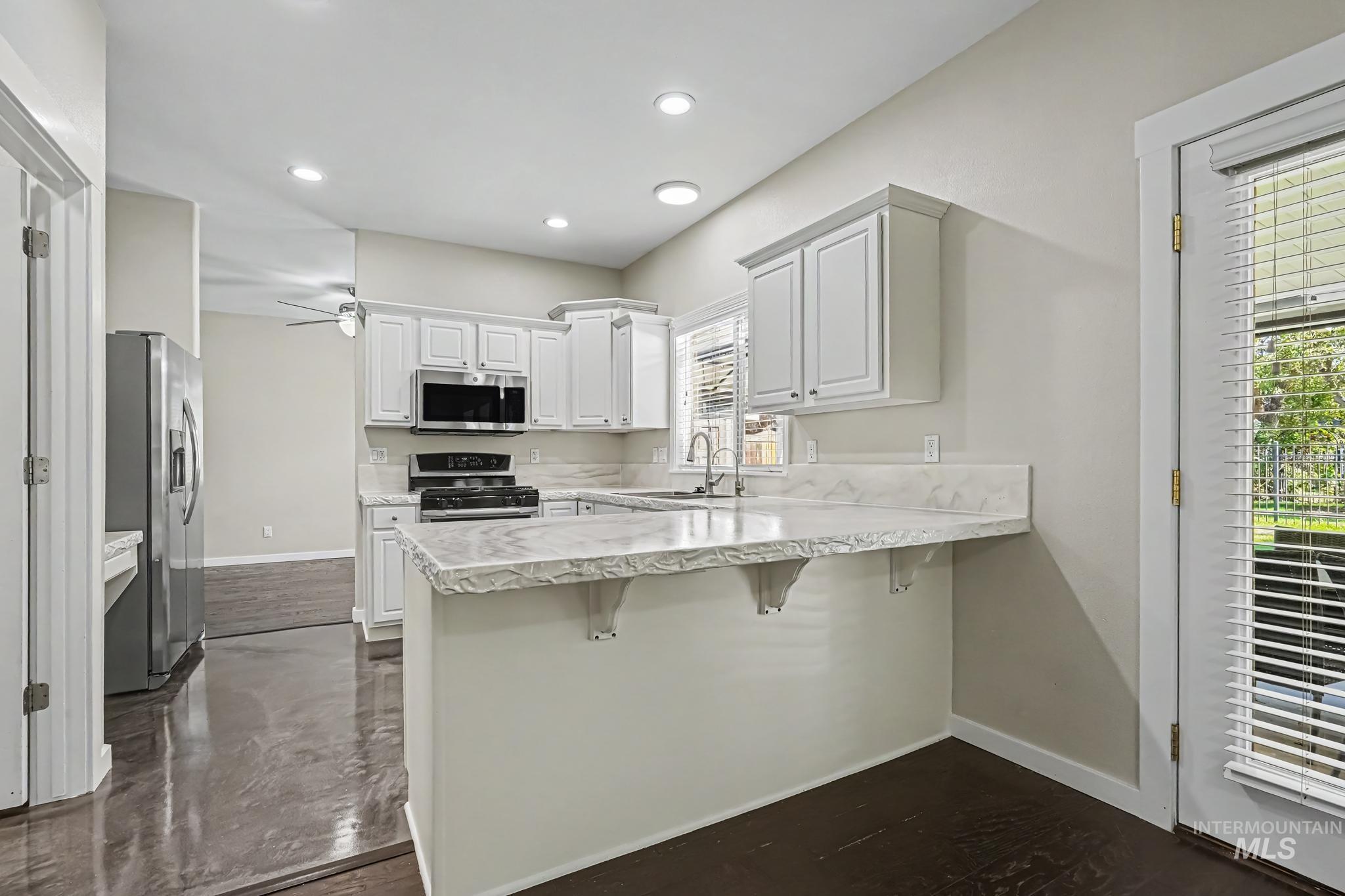 14421 West Stockwell Street Boise, ID 83713 - Photo 3 of 20 Contemporary kitchen featuring white cabinetry, light-colored countertops, stainless steel appliances, recessed lighting, and dark wood-finish flooring