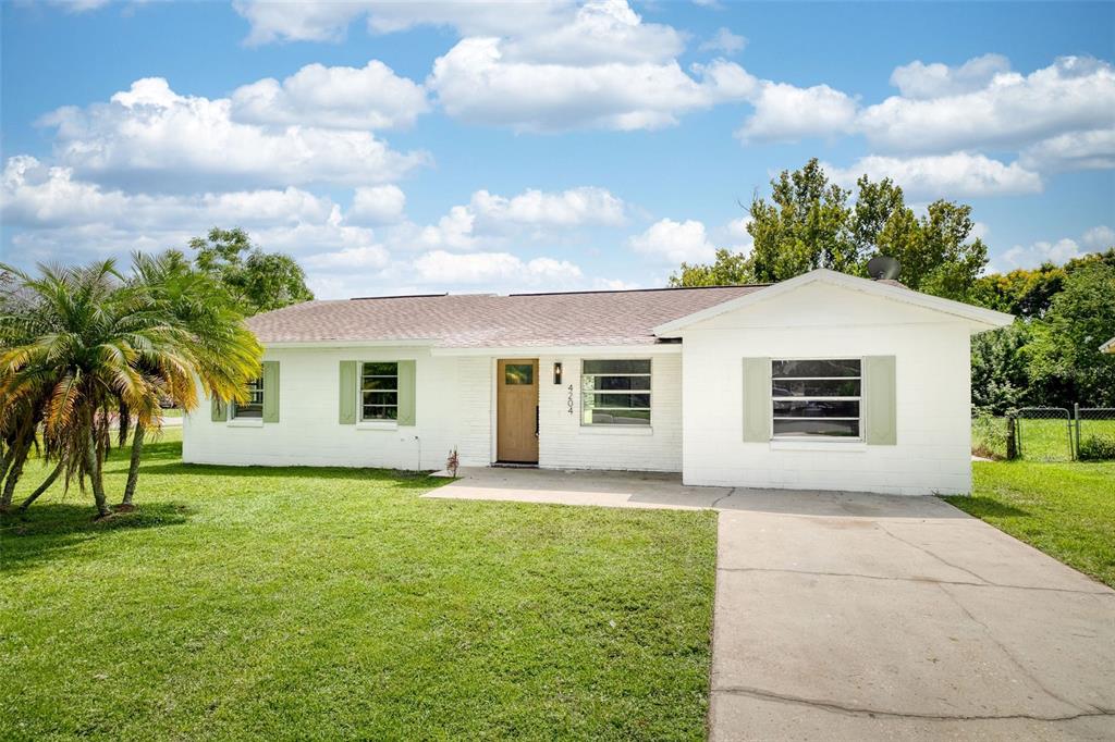 a view of a yard in front of a house with a large tree