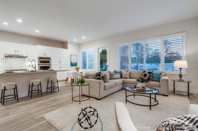 a living room with furniture kitchen view and a large window